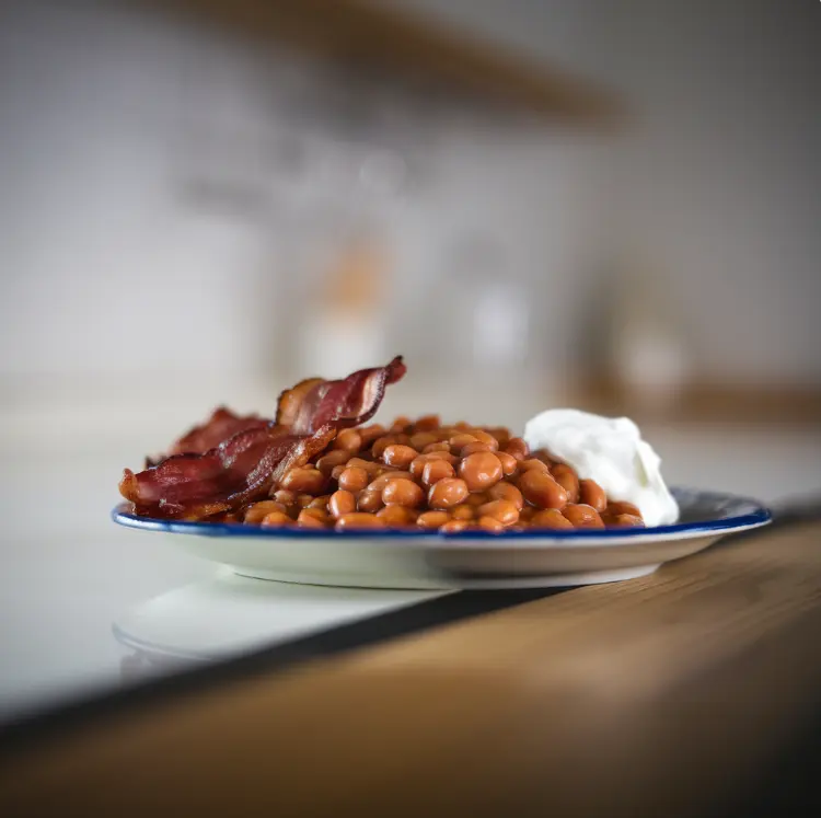 Delicious baked beans with bacon and herbs in a bowl.