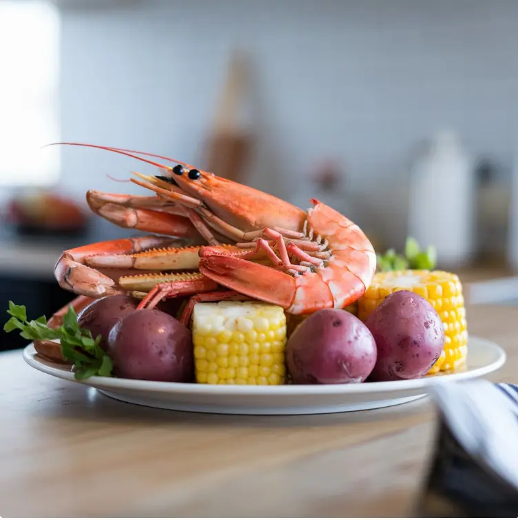 Seafood boil with shrimp, crab legs, corn, and potatoes served in a rustic outdoor setting.