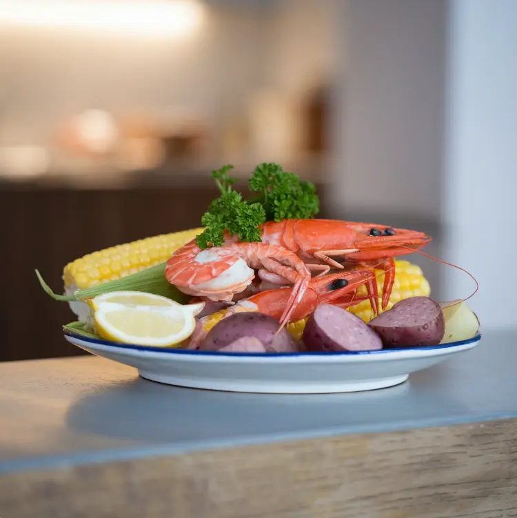 A seafood boil spread with shrimp, crab legs, potatoes, corn, and sides like garlic bread and coleslaw on a rustic table.